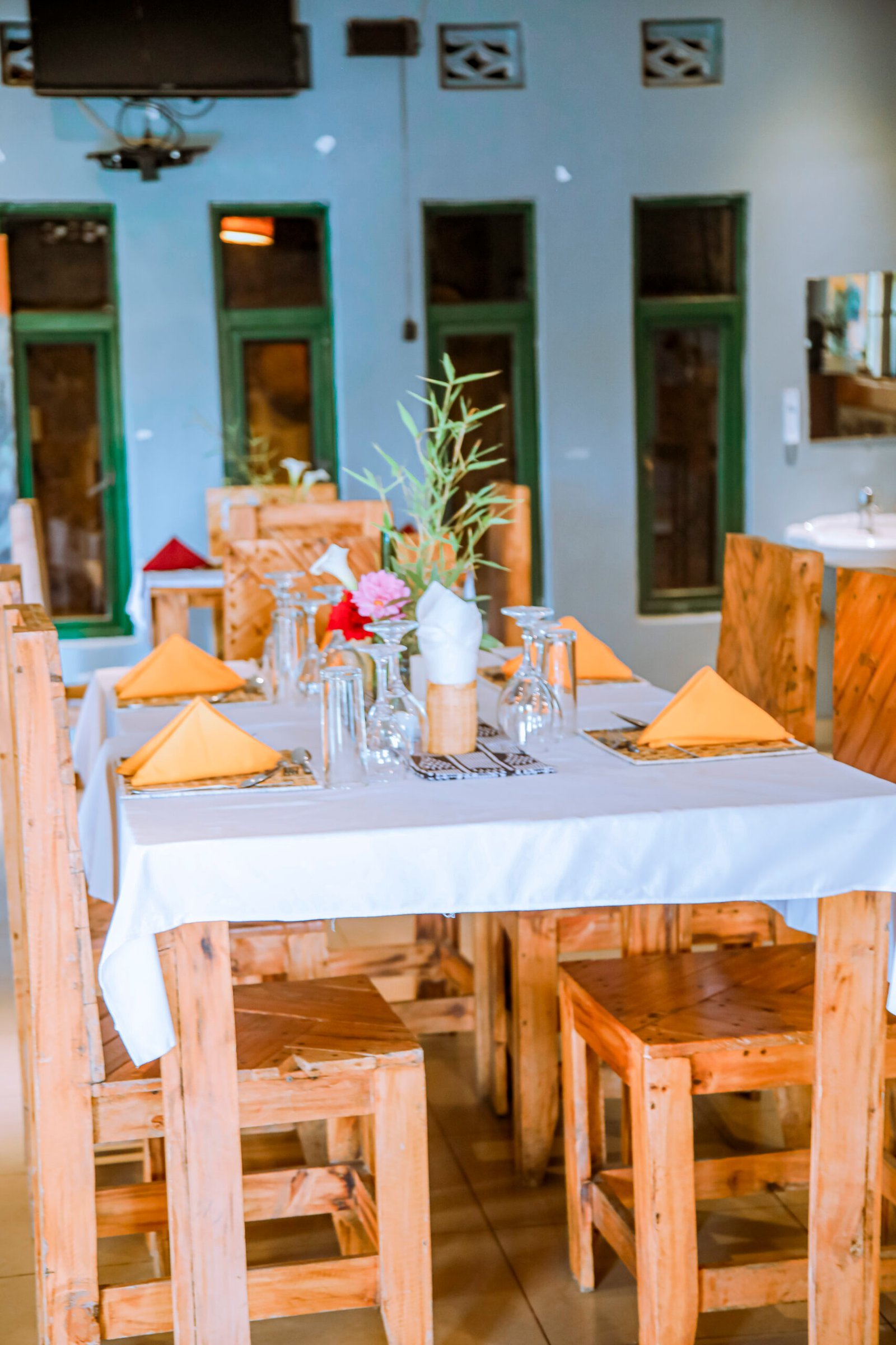 Table set with orange napkins, glassware and a small flower arrangement