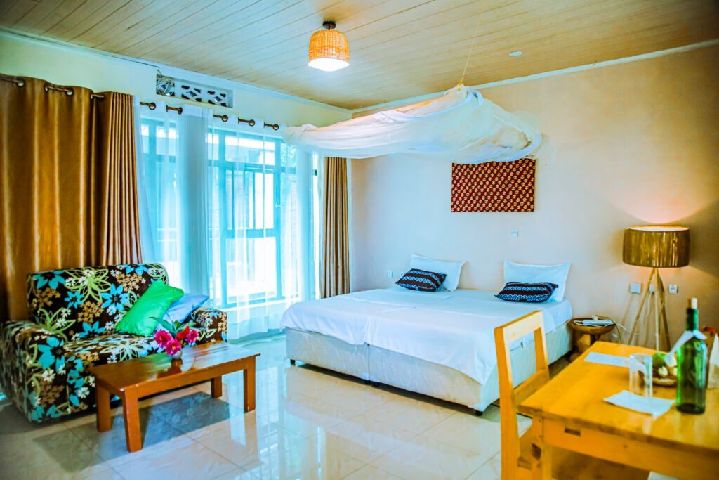 Spacious room with a double bed, floral lounge chair and sheer window curtains