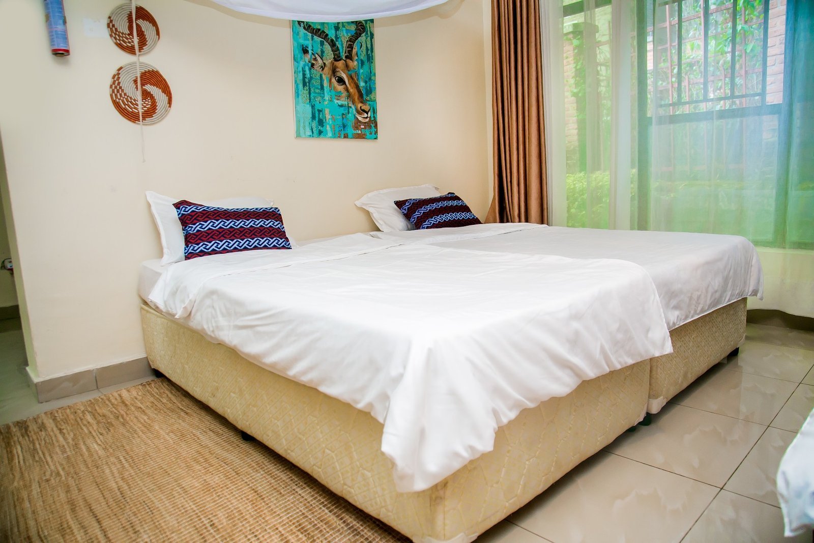 Single room with a white bed, antelope painting and woven wall baskets